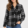 a woman wearing a black and ivory plaid collared shirt and blue jeans on a white background.