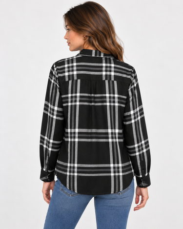 a woman wearing a black and ivory plaid collared shirt and blue jeans on a white background.