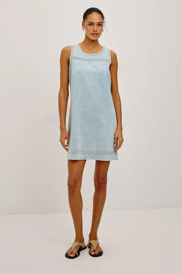 Woman wearing a light blue denim dress on a white background