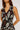 Woman wearing a sleeveless dress with a brown and white pattern on a plain background