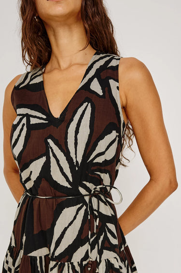 Woman wearing a sleeveless dress with a brown and white pattern on a plain background