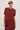 A model wearing a short-sleeve button-front knit cardigan in a deep burgundy red, paired with a matching skirt and sunglasses, against a plain light gray studio background.