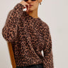 Person wearing a leopard print sweater against a plain background