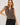 Woman wearing a brown striped sleeveless top and black pants on a white background