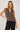 Woman wearing a brown striped sleeveless top and black pants on a white background