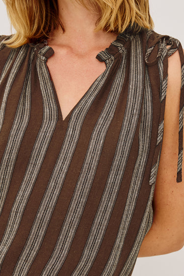 Close-up of a person wearing a brown and gray striped sleeveless top on a white background