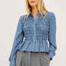Woman wearing a blue striped shirt and gray pants on a white background