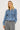 Woman wearing a blue striped shirt and gray pants on a white background