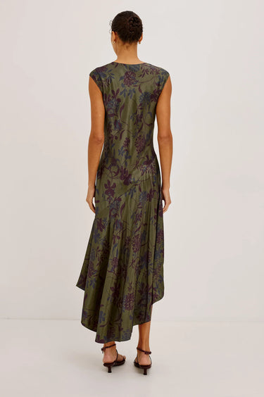 A woman wearing a olive floral midi dress and burgundy heels on a white background.