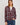 A woman modeling a long-sleeve button-front plaid shirt in burgundy, gray, and white, paired with blue jeans against a light gray studio background.