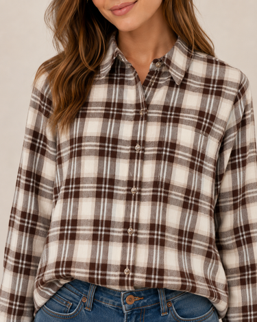A woman wearing a brown and cream plaid button-down shirt with blue jeans, cropped from the chin down against a plain light background.