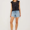 Woman wearing a black sleeveless top and denim shorts on a white background