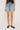 a woman wearing a black top and light blue denim shorts on a white background