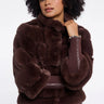 Woman wearing a brown fur coat against a white background