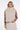 Woman wearing a beige fur vest over a brown long-sleeve top on a white background