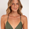 Woman wearing a green bikini top against a plain background