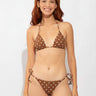 Woman wearing a brown polka dot bikini against a white background