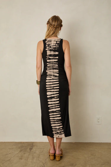 Woman wearing a black dress with a unique tie-dye Zeber’s pattern, standing against a plain wall.