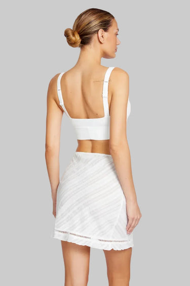 Woman wearing a white sports bra and skirt set on a white background