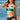 Woman wearing a green and navy bikini standing on a beach with ocean waves in the background