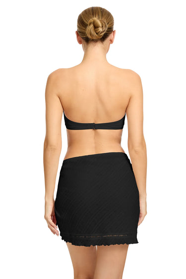 Woman wearing a black strapless top and skirt on a white background