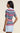 a woman wearing a zig zag stripe polo shirt with blue shorts on a neutral background