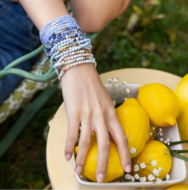 A woman wearing a stack of semi precious stone necklaces double wrapped as bracelets