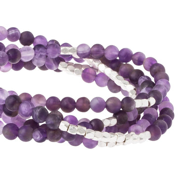 Purple amethyst gemstone beads with silver faceted spacer beads, arranged in multiple strands on a white background.