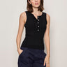 a woman wearing a black henley tank top and blue pants on a white background