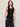 a woman wearing a black henley tank top and blue pants on a white background