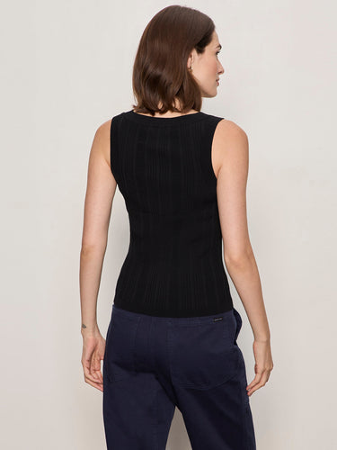 a woman wearing a black henley tank top and blue pants on a white background