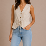 Woman wearing a beige ribbed vest and light blue jeans against a beige background