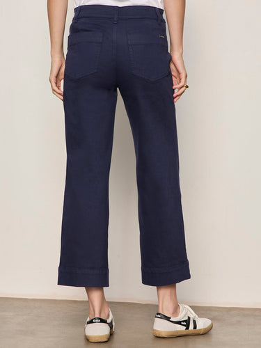 A woman wearing navy blue cropped pants on a neutral background