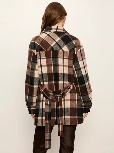 A model shown from the back wearing a brown, beige, and black plaid wrap coat with a tie belt, paired with dark brown pants, against a plain off-white background.