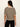 A woman shown from the back wearing a short-sleeve knit top with horizontal black and beige stripes, paired with black pants, against a plain off-white background.