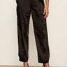 Black wide-leg trousers with a satin-like sheen, shown on a model wearing black slingback heels against a neutral studio background.