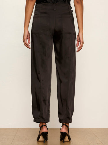 Rear view of a model wearing dark brown wide-leg trousers with a high waist, cuffed ankles, and side cargo pockets, paired with black high-heeled sandals.