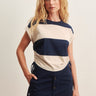 A woman wearing a rugby-reminicient striped shirt in navy and opal with ruched side details and a navy blue skirt