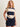 A woman wearing a rugby-reminicient striped shirt in navy and opal with ruched side details and a navy blue skirt