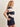 A woman wearing a rugby-reminicient striped shirt in navy and opal with ruched side details and a navy blue skirt