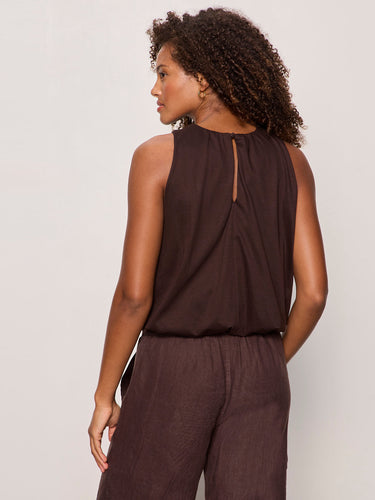 Woman wearing a brown sleeveless top and pants on a plain background