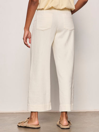a woman wearing wide leg off white pants on a neutral background