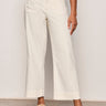 a woman wearing wide leg off white pants on a neutral background