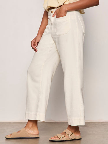 Person wearing white pants and beige sandals on a plain background