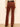 Rust brown corduroy flare pants shown from the back on a model wearing a cream lace top and black belt.