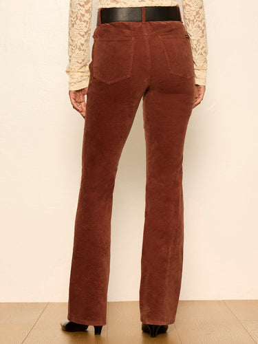 Rust brown corduroy flare pants shown from the back on a model wearing a cream lace top and black belt.