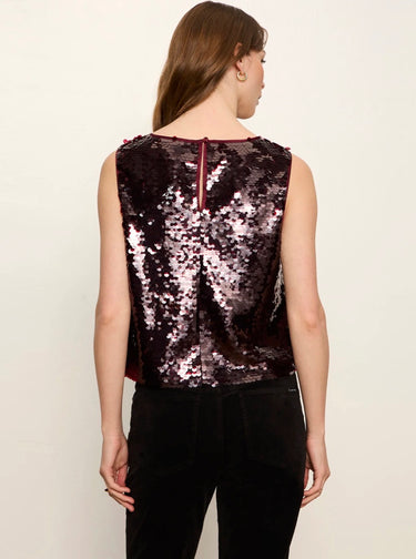 A woman shown from the back wearing a sleeveless sequined top with a deep V-neckline and black pants, set against a plain off-white background.