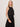 Woman wearing a black sleeveless top and black pants against a plain background