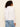 Person wearing a white shirt and blue jeans against a beige background