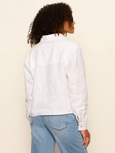 Person wearing a white shirt and blue jeans against a beige background